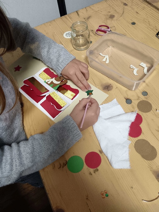 Des mains découpent et assemblent un marque-page à une table d’atelier.