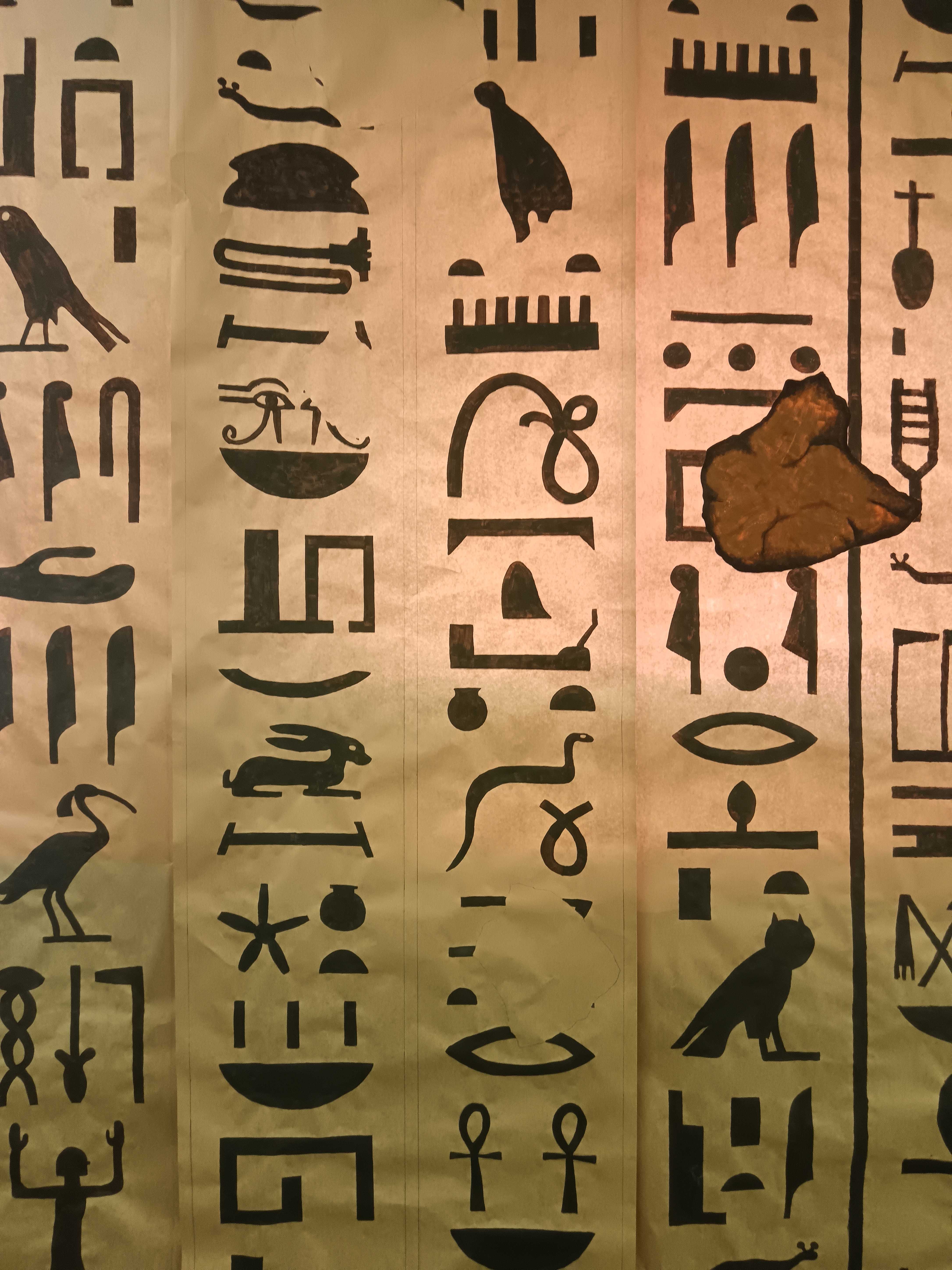 Détail du décor de l’escape game : des colonnes de hiéroglyphes noirs sur un fond couleur papyrus.